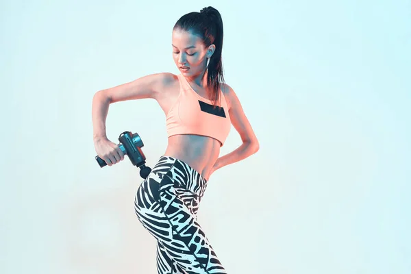 Perküsyon masaj aleti, genç fit kadın masaj kalçası egzersiz öncesi ısınma için kalça, fotokopi alanı olan fotoğraf.