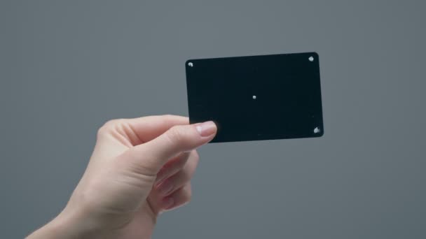 Carte bancaire en plastique noir avec points de suivi à la main féminine sur fond de studio gris, vidéo publicitaire — Video