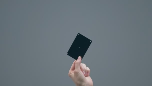 Mano delle donne che mostrano carta di credito in plastica nera con punti di tracciamento su sfondo grigio studio con spazio copia — Video Stock