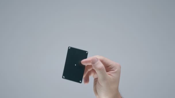 Male hand showing black plastic bank or gift card with tracking points on gray studio background — Αρχείο Βίντεο