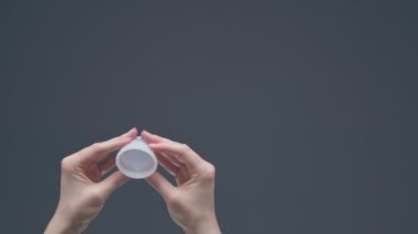 Tekrar kullanılabilir adet bardağını katlayan kadın eller. Sıfır adet hijyeni. Periyotlar için çevre dostu alternatif