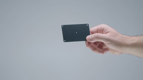 Black plastic bank or gift card with tracking points in male hand on gray studio background — Stock Video