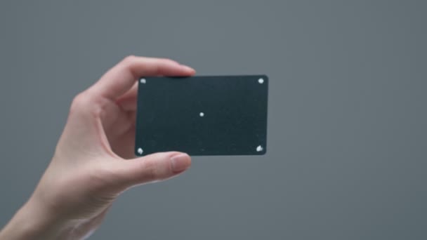 Banco nero carta di credito o di debito con punti di tracciamento e spazio vuoto in mano femminile su sfondo grigio studio — Video Stock