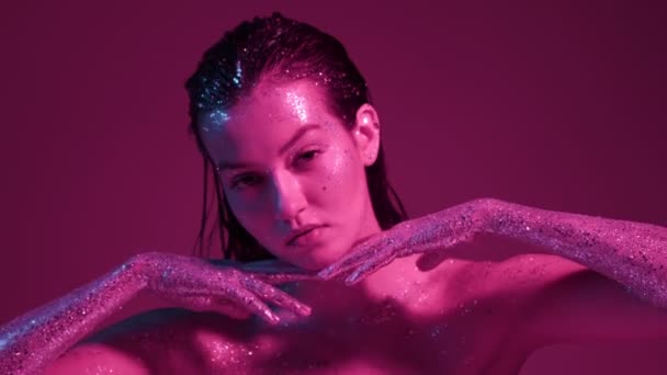 Alta moda feminina em brilhos em luz de néon rosa posando em estúdio, linda menina sexy com brilho corpo arte — Vídeo de Stock