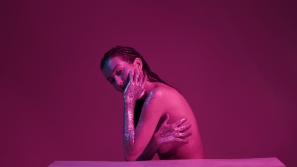 Nackte weibliche Mode-Model in funkelt in rosa Neonlicht posiert im Studio, sexy Mädchen mit glitzernden Körperkunst — Stockvideo