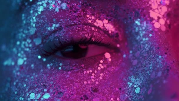 Kobieta mruga okiem pod światłem neonowym 4K. Dziewczyna z pięknym błyszczącym makijażem, zbliżenie. Nocne życie, koncepcja klubu nocnego. — Wideo stockowe