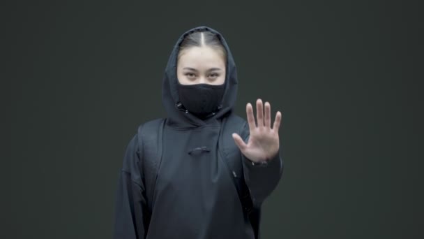 Kvinna i svart mask visar defensiv hand gest. Könsdiskriminering protest mot övergrepp, våld i hemmet — Stockvideo