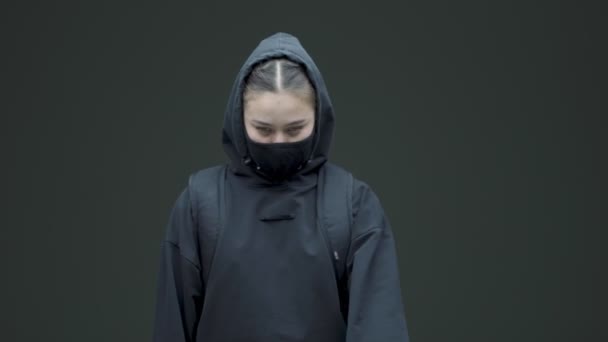Memprotes wanita feminis dalam topeng hitam dan hoodie menunjukkan sikap berhenti untuk diskriminasi gender di latar belakang studio abu-abu — Stok Video