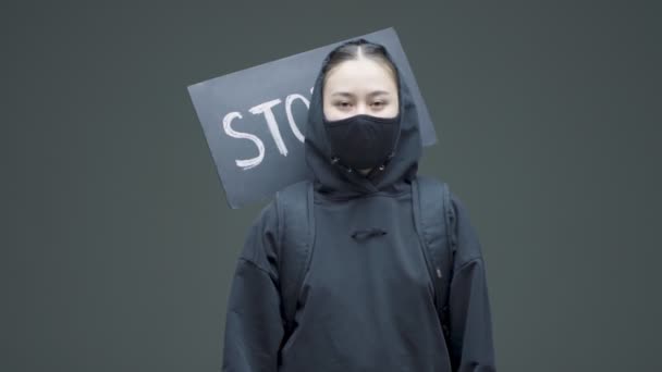 Female protestor in black mask folds arms over chest in defensive gesture against gender discrimination — Stock Video