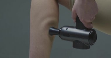 Perküsyon masaj aleti, kadın el masajı. Stüdyoda masaj tabancasıyla alt bacak masajı. Antrenman öncesi ısınma.