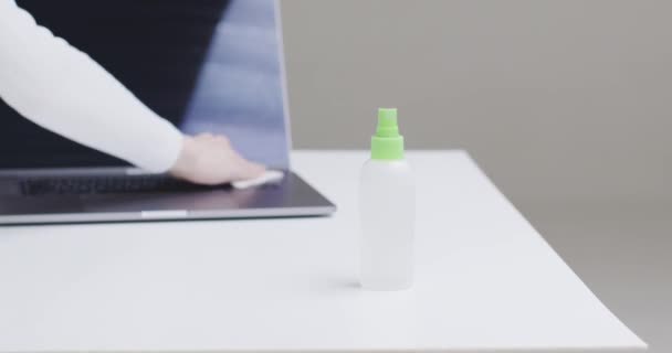 Närbild kvinnlig hand sanera arbetsplatsen desinficera laptop tangentbord, skärm genom att torka för att stoppa covid — Stockvideo