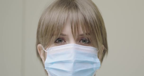 Primer plano médico femenino serio en azul protector mascarilla médica mirando a la cámara durante la pandemia coronavirus — Vídeos de Stock