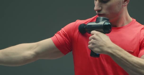 Athletic guy massaging shoulder by handheld percussion massage gun to relieve joint pain, close up — Stock Video