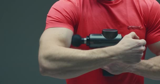 Masážní tělocvična, zblízka masážní biceps mužského pohlaví masážní pistolí ve studiu, předcvičné zahřívání — Stock video