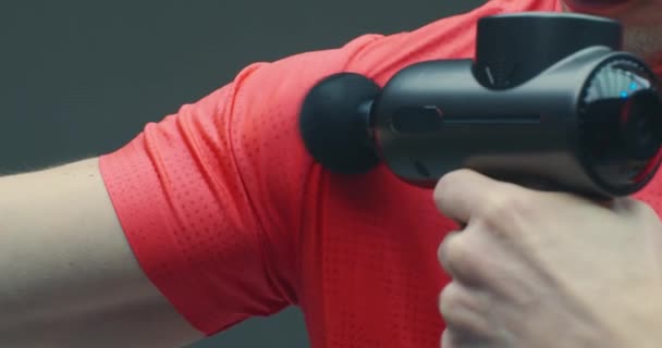 Guy μασάζ άρθρωση ώμου με το χέρι κρουστά όπλο μασάζ για να ανακουφίσει τον πόνο, την προώθηση της κυκλοφορίας, κοντά — Αρχείο Βίντεο