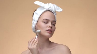 Sağlıklı ciltli güzel bir kadın gua sha Jade Quartz roller ile yüz masajı yapıyor. Cilt bakımı ve doğal güzellik
