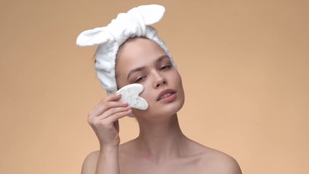 Mooi jong meisje masseren gezicht door schoonheid gua sha steen voor tillen. Cosmetische natuurlijke trend, anti-aging massage — Stockvideo