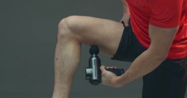 Perküsyon masajcısı, sporcu adam kalça masajı yapıyor kas sertliğini azaltmak için, egzersiz sonrası iyileşme rutinleri...