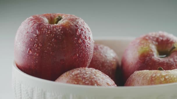 Ręcznie umieścić eco pół ugryzione jabłko diety w krople wody wazon z kupą organicznych czerwonych całych owoców, zbliżenie studio wideo — Wideo stockowe