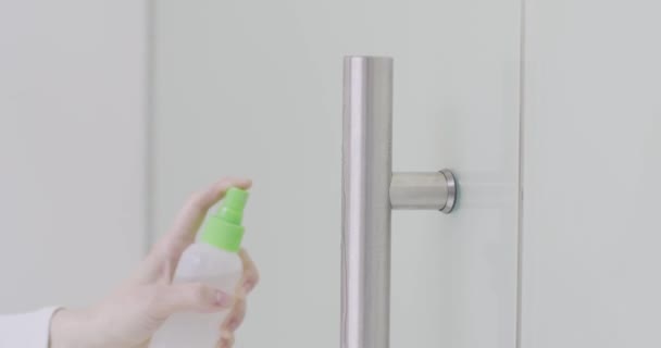 Женская ручная чистка и дезинфекция дверной ручки офиса с помощью дезинфицирующего спрея и влажной салфетки, чтобы предотвратить ковид-19 — стоковое видео