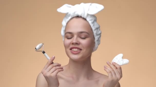 Cosmetische natuurlijke trend, lachende jonge twintiger jaren meisje met een gezonde huid, beauty jade roller en steen voor massage — Stockvideo