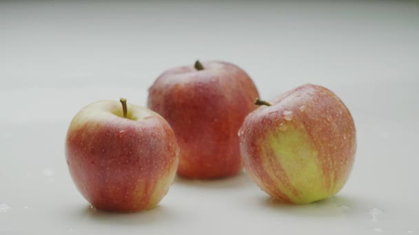 Maçãs naturais em gotas de água abaixo do córrego de água que flui no montão de frutos apetitosos vermelhos orgânicos — Vídeo de Stock