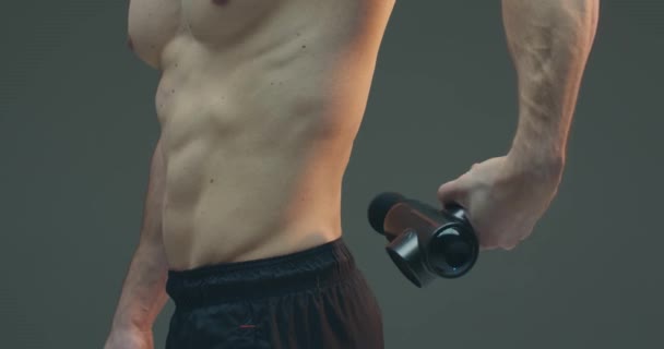 Tiefengewebe-Perkussionsmassage, athletischer Typ massiert unteren Rücken zur Schmerzlinderung auf grauem Studiohintergrund — Stockvideo
