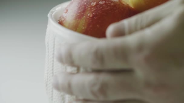 Mani messo vaso con eco mele naturali in gocce d'acqua sul tavolo, mucchio di frutti interi rossi biologici, close up studio video — Video Stock