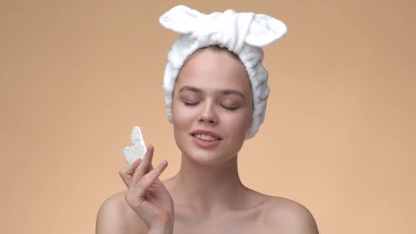 Concetto di bellezza naturale, giovane ragazza massaggiare la pelle sana del viso di bellezza gua sha pietra di quarzo su sfondo beige — Video Stock