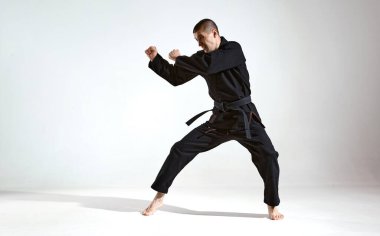 Siyah kimonolu dövüşçü stüdyo arka planında fotokopi alanı ve dövüş konsepti ile karate tekniği gösteriyor.