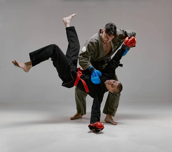 Kimono ve boks eldivenli iki dövüşçü savaş sırasında nakavt, dövüş sanatları, karışık dövüş konsepti. — Stok fotoğraf