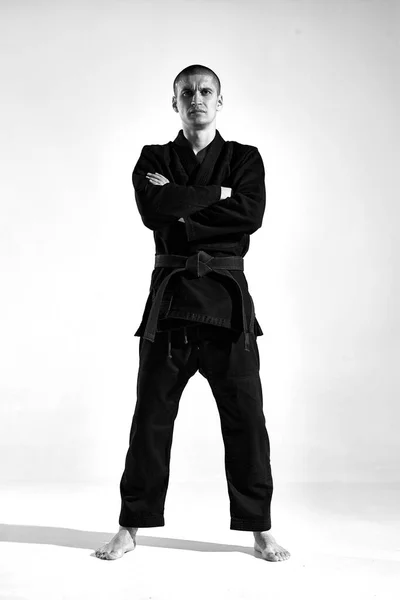 Sportlertyp im Kimono-Kämpfer posiert in Karate-Haltung auf Studiohintergrund mit Kopierraum, Schwarz-Weiß-Porträt — Stockfoto