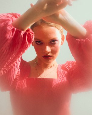 Pembe bluz içinde romantik stil sahibi genç bir bayan model. Altın mücevherler, güzel bir kızın stüdyo resmi.