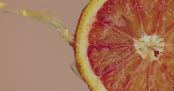 Nahaufnahme Orangensaft fließt auf natürlichen Früchten auf rosa Studiohintergrund mit Kopierraum, frische köstliche Vitamine — Stockvideo