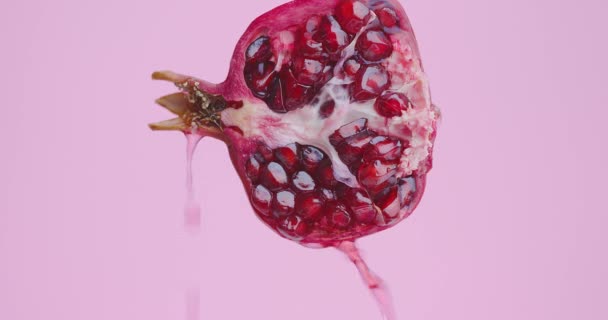 Juice flyter ner på naturliga granatäpple frukt på rosa studio bakgrund med kopia utrymme, hälsosam kost koncept — Stockvideo