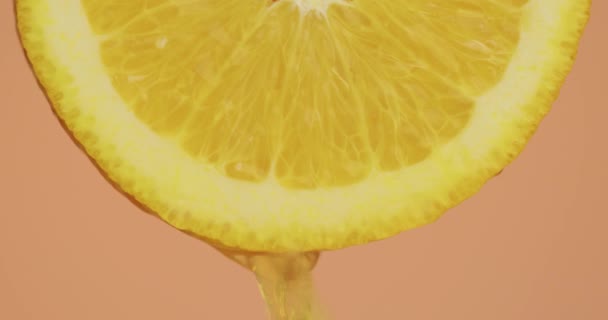 Nahaufnahme von gelbem Saft fließen nach unten auf natürliche Bio-Orangenfrüchte auf rosa Studiohintergrund, frische köstliche Vitamine — Stockvideo