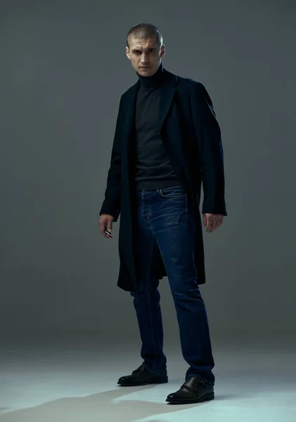 Siyah ceketli yakışıklı genç adamın portresi. Gri stüdyo arka planında stil sahibi bir iş adamı.