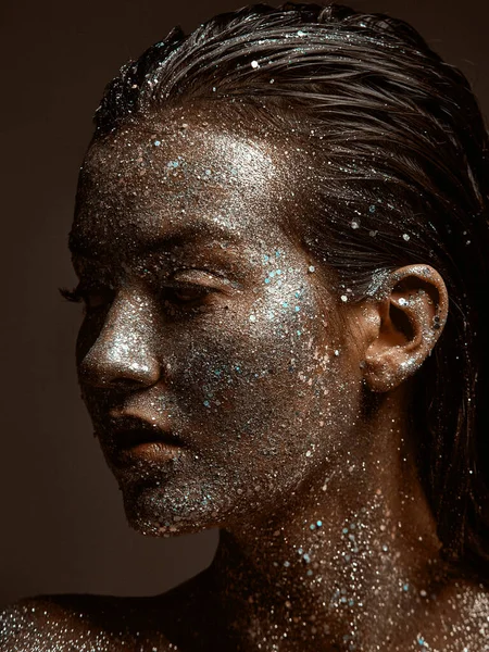 Zilveren sprankelend vrouwelijk gezicht, jong meisje poseren met feestelijke gloeiende glinsterende make-up close-up studio portret — Stockfoto