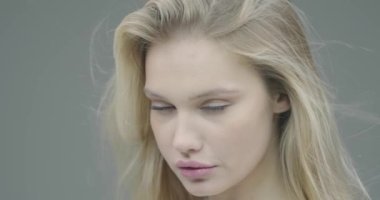 Gülümseyen genç kız doğal güzelliğin tadını çıkarıyor, sağlıklı, yumuşak nemlendirilmiş cilt ve uzun, saf sarı saçlar, yakın çekim.