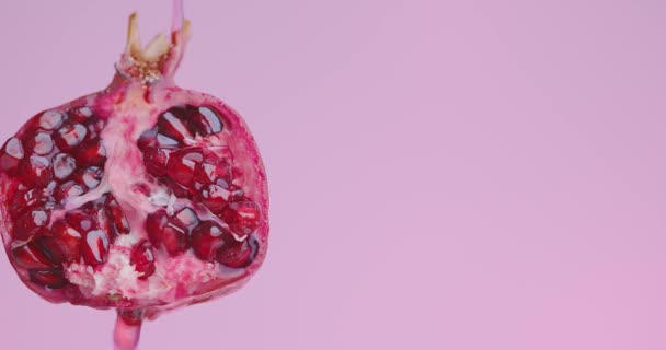 Succo o vino scorre giù su frutta melograno naturale su sfondo rosa studio con spazio copia per la pubblicità — Video Stock