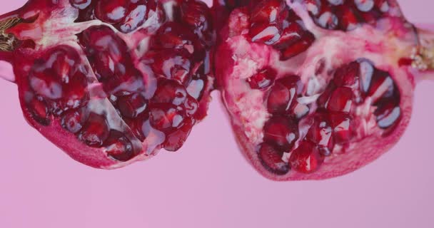 Succo o vino scorre su frutta melograno su sfondo studio rosa con spazio copia, primo piano — Video Stock