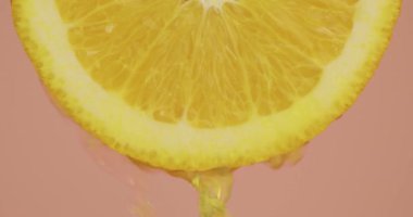 Portakal suyu, pembe stüdyo arka planında doğal biyo-turunçgil meyvesine akar. Taze lezzetli vitaminler, yakın plan.