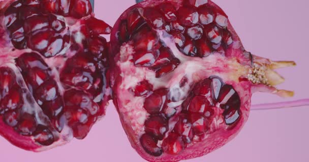 Сік, що ллється на гранатових фруктах на рожевому фоні студії, крупним планом відео, здорове апетитне харчування — стокове відео