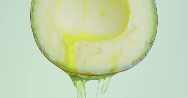 Öl fließt von entsteinten Avocado auf grünem Studiohintergrund mit Kopierraum, vegetarische gesunde Ernährung, Nahaufnahme — Stockvideo
