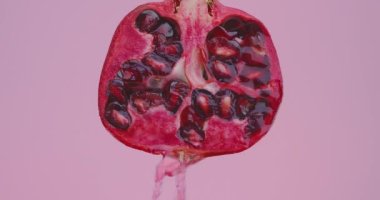 Meyve suyu ya da şarap damlaları pembe stüdyo arka planında doğal nar meyvesi üzerine akar. Fotokopi alanı ve taze vitaminlerle.