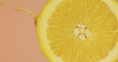 Dikey video. Meyve suyu, pembe stüdyo arka planında doğal portakal meyvesi üzerine akar. Taze lezzetli yaz vitaminleri, kapatın.
