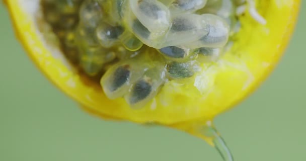 Close up video granadilla juice flow down from passion fruit pulp on green studio background, healthy eating concept — Stock Video