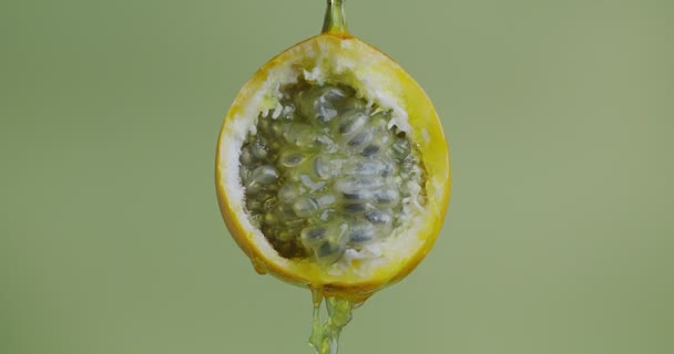 Close up vídeo de suco de granadilla ou água flui para baixo de maracujá amarelo natural no fundo do estúdio verde — Vídeo de Stock