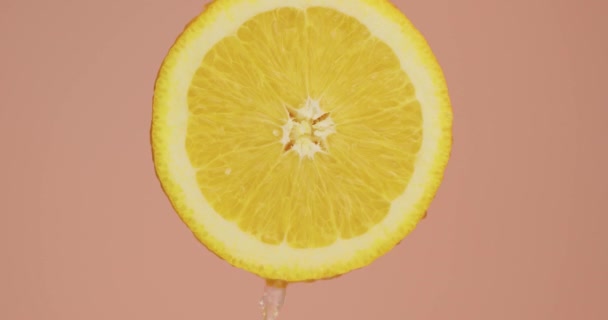 Vatten droppar flyter ner på naturliga bio apelsin frukt på rosa studio bakgrund med kopia utrymme, färska läckra vitaminer — Stockvideo
