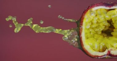 Dikey video. Çarkıfelek meyvesi suyu, kırmızı stüdyo arkaplanındaki doğal hamurdan akarak fotokopi alanına dönüşür.